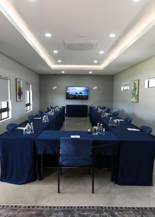 Wide view of U-shaped conference room with navy tables and wall screen