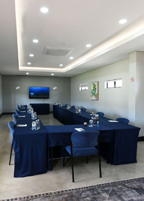 U-shaped conference table setup with navy linens and wall-mounted screen