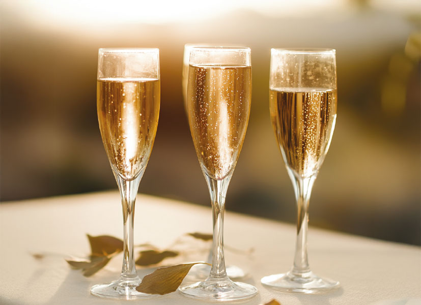 Three champagne flutes filled with sparkling wine at golden hour